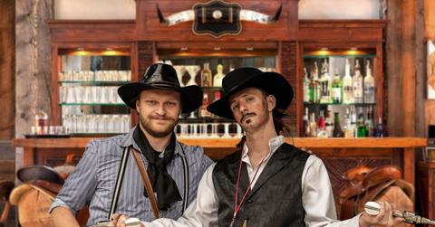 Two people dressed in Old West clothes holding guns