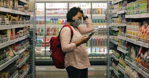 A woman grocery shopping and looking at the prices