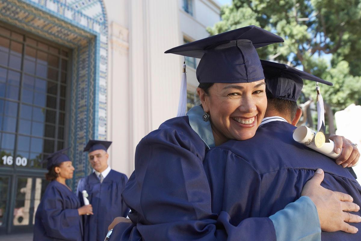 Graduates in mortarboards hugging