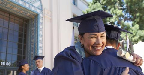 Graduates in mortarboards hugging