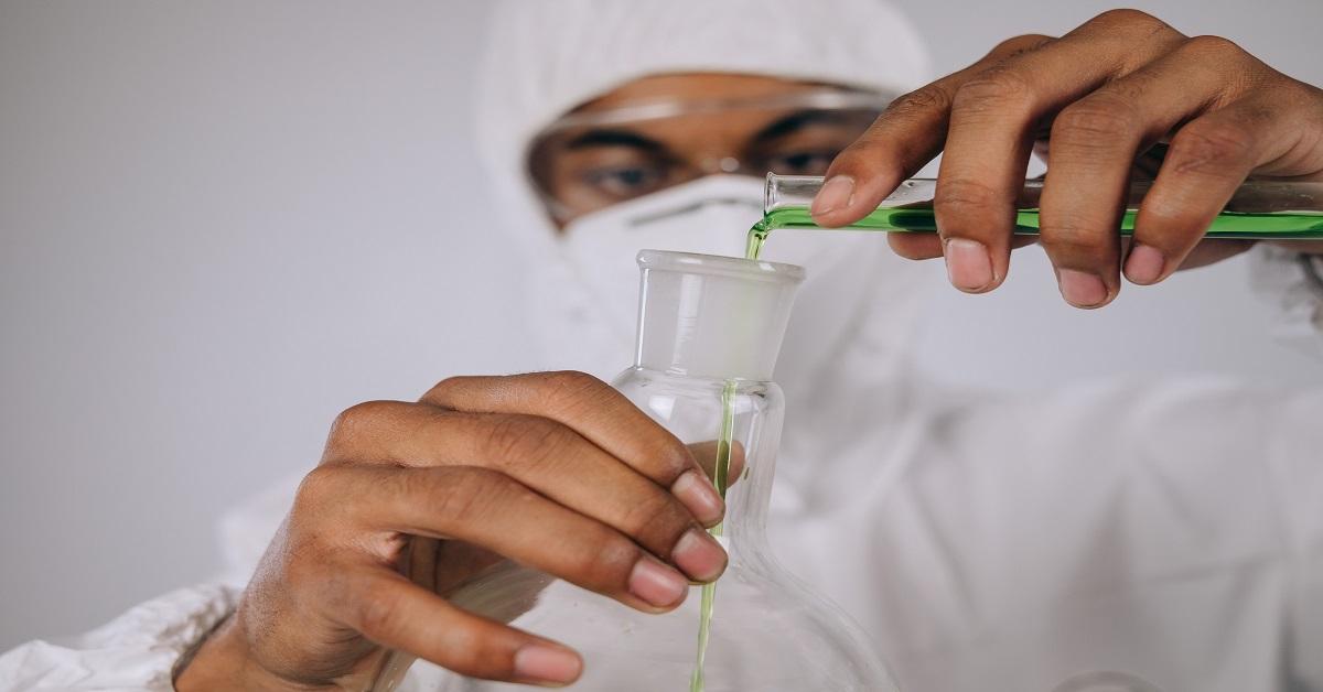 A person pouring a solution into a beaker in a lab