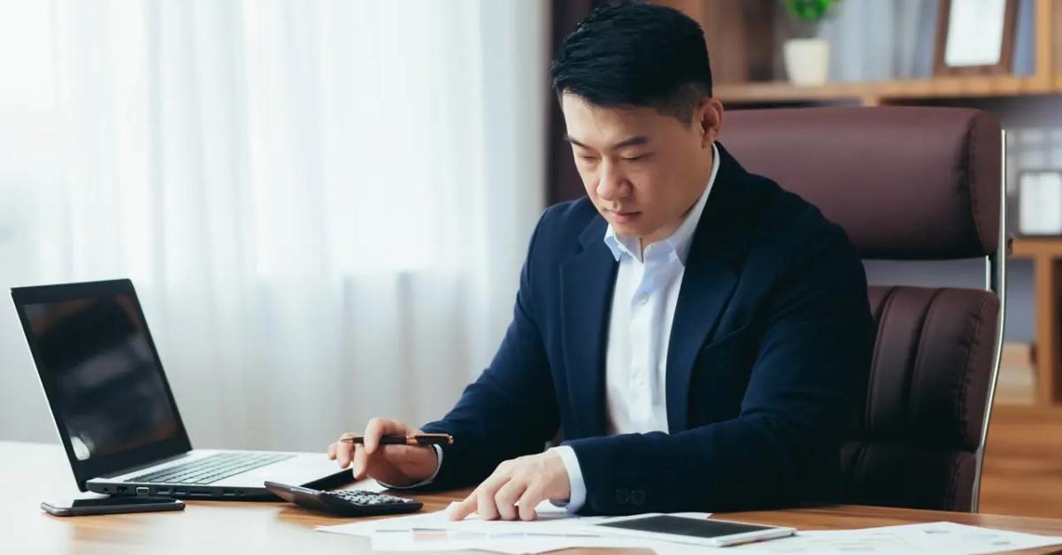 A businessman sitting at his desk calculating his budget.