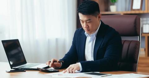 A businessman sitting at his desk calculating his budget.