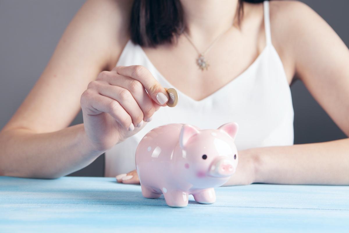 A woman putting a coin in a piggy bank