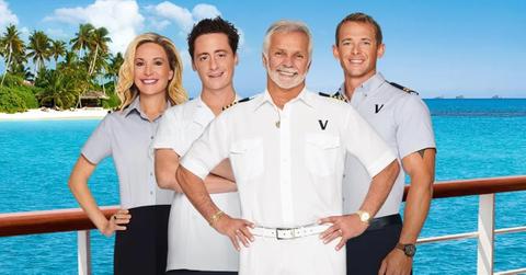 Four 'Below Deck' cast members stand on a boat in the water.