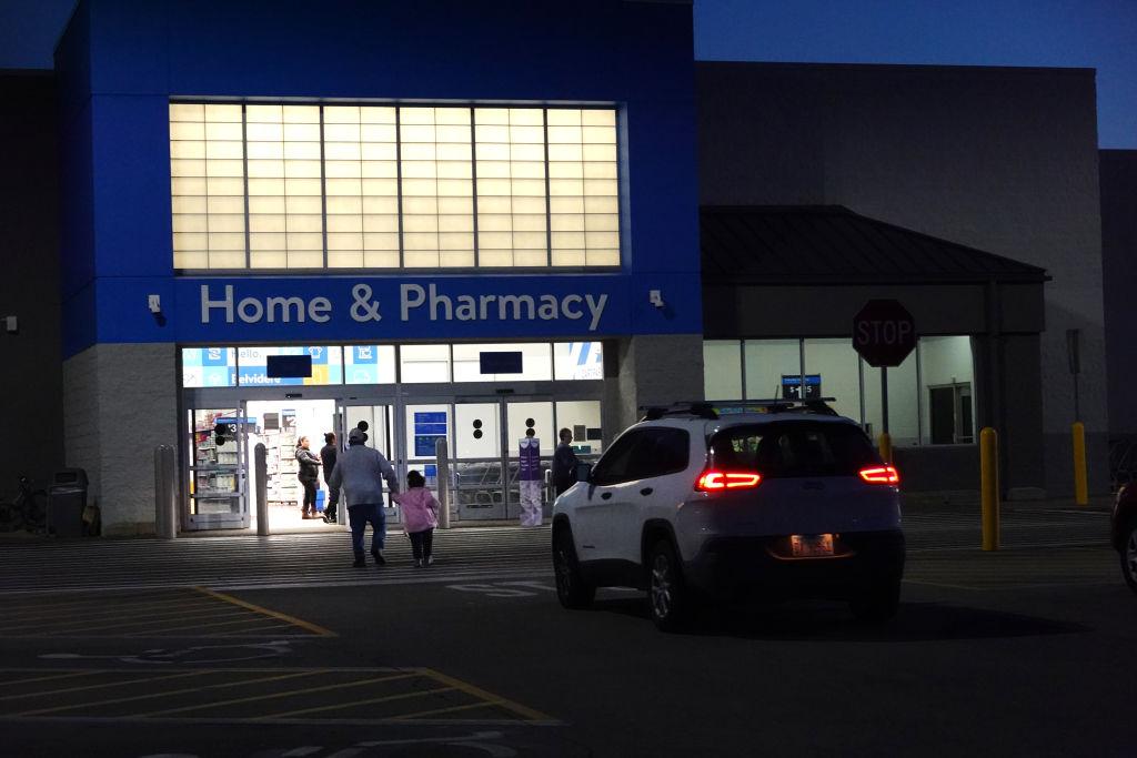 Two people walking into Walmart at night