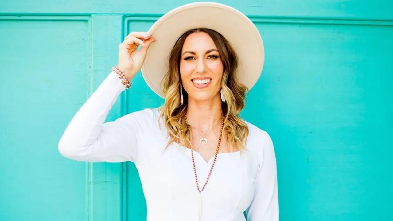 Emily Wilcox wearing a hat and standing in front of a turquoise wall