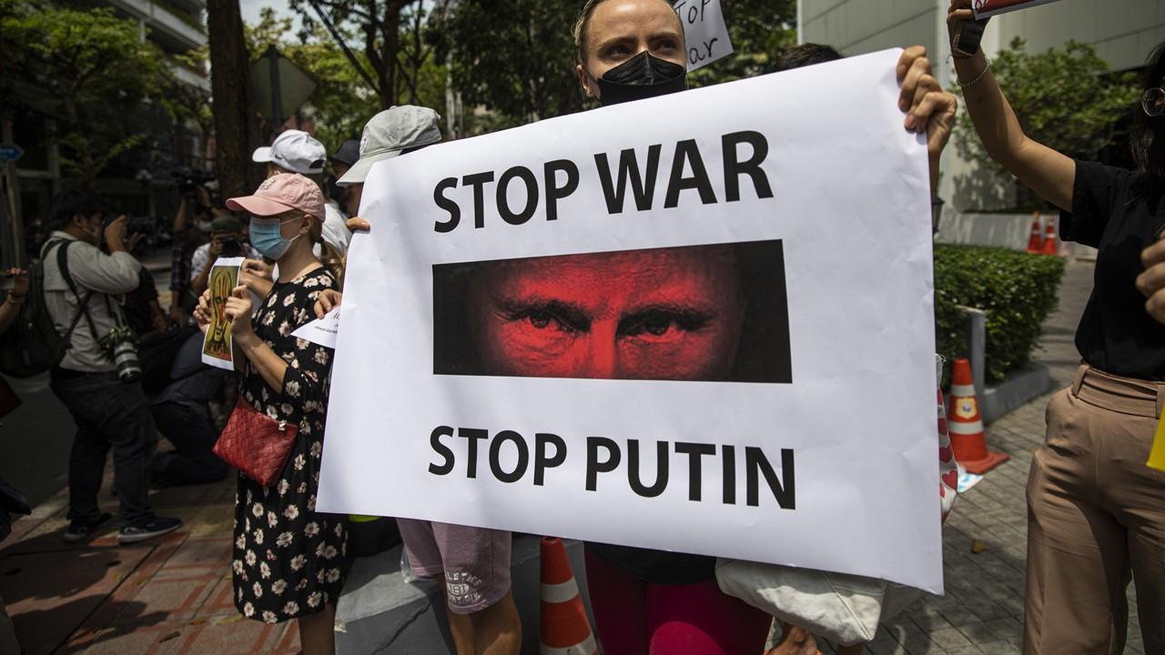 A woman holding a sign protesting the Russia-Ukraine war and Putin