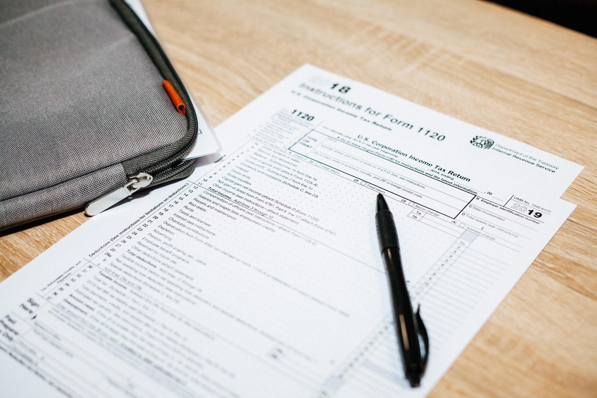 A black pen sits on a unmarked 1120 tax form 