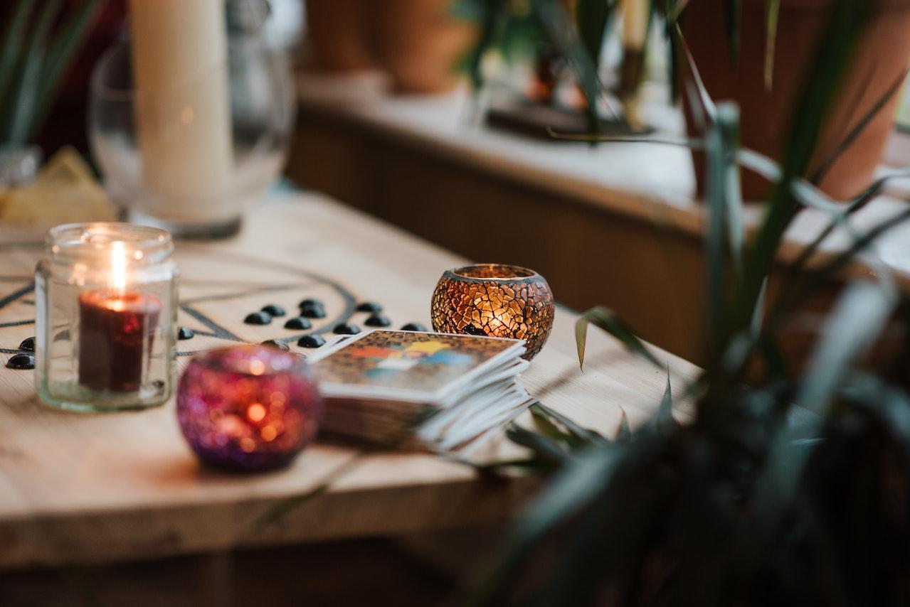 A set of tarot cards and glowing candles on a table 