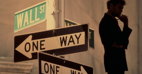 Man standing next to a Wall Street sign