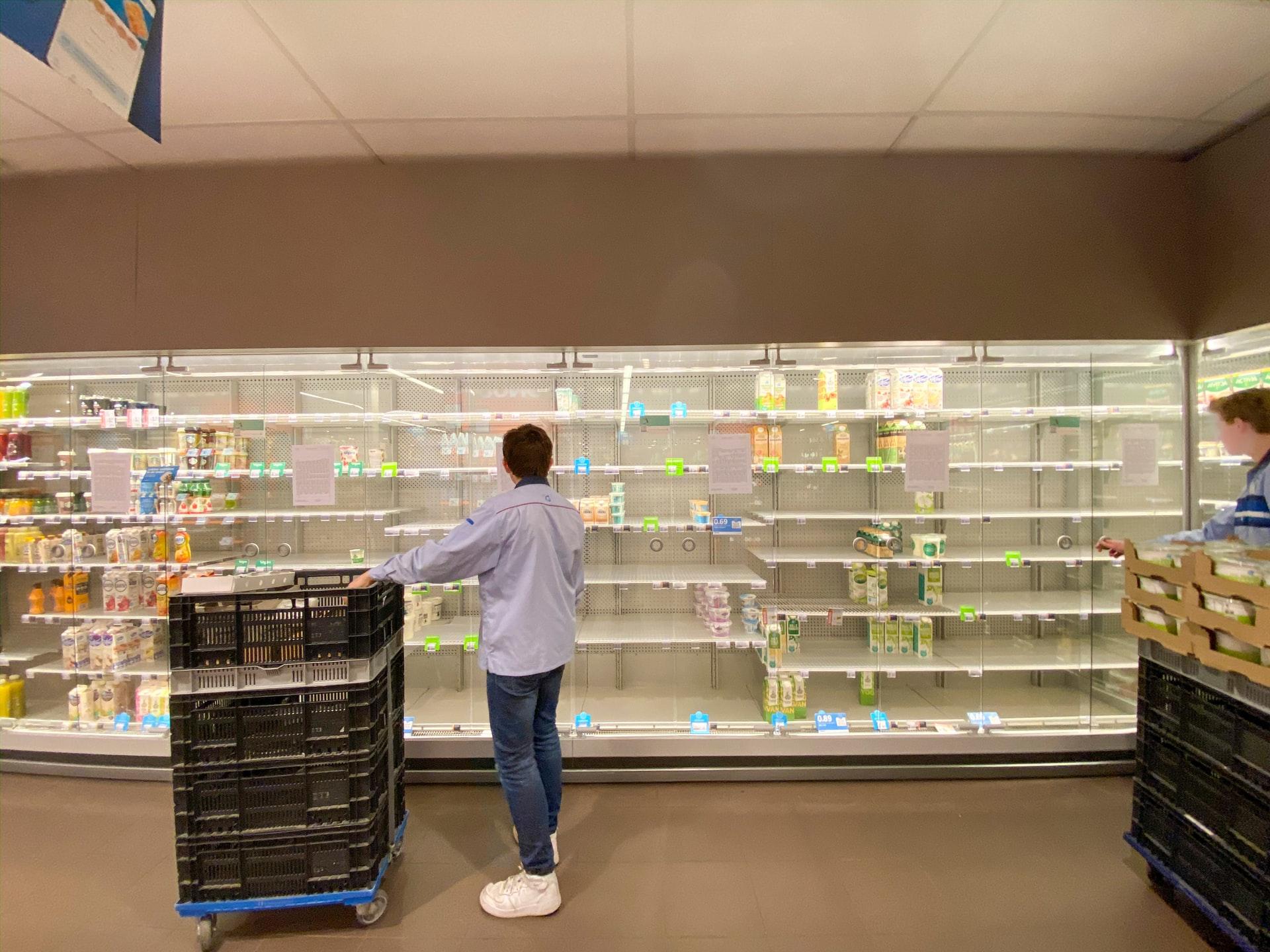 A person looking at empty supermarket shelves