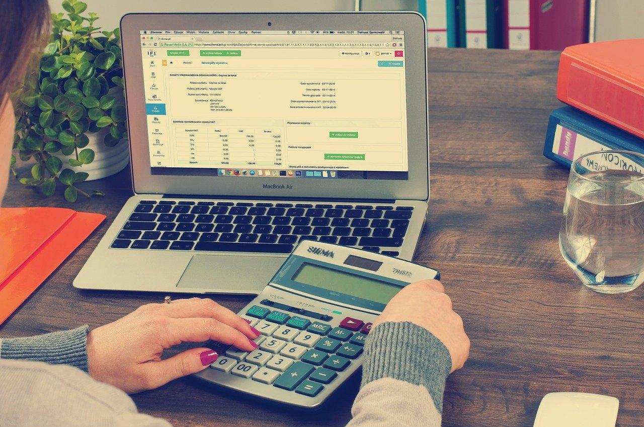 A woman calculating taxes on a calculator and a computer