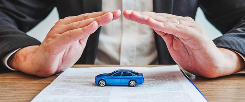 A toy car on top of car insurance forms