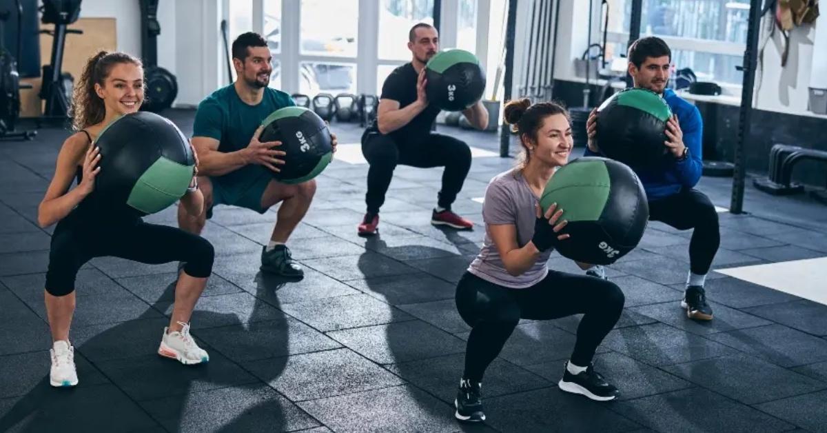 A group of people working out together and using weighted balls at the gym.