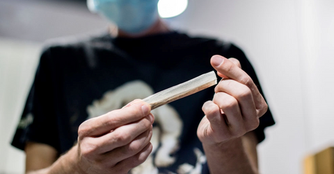 Person at marijuana dispensary rolling cannabis joint