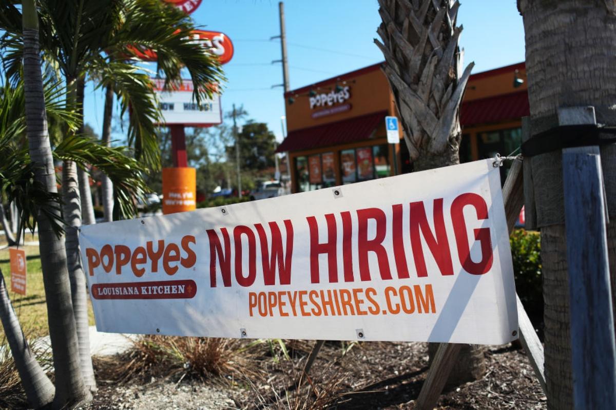 A "now hiring" sign outside a Popeyes restaurant, one sign that employers are having trouble finding employees willing to work for current wages.