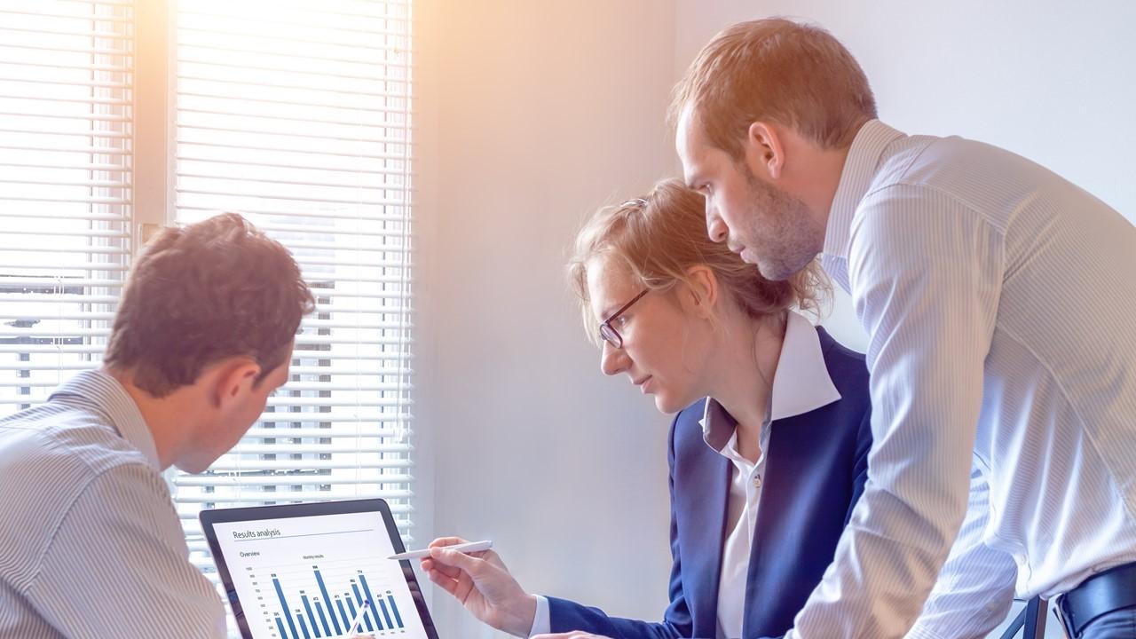 Two men and a lady reviewing data on a laptop