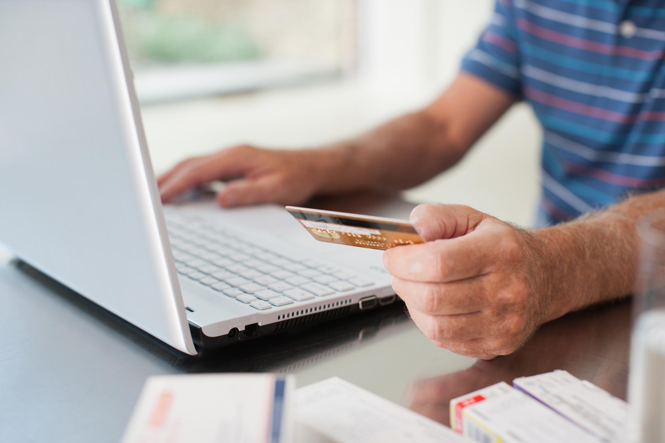 A person holding a credit card while using a laptop