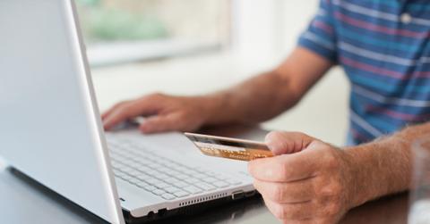 A person holding a credit card while using a laptop