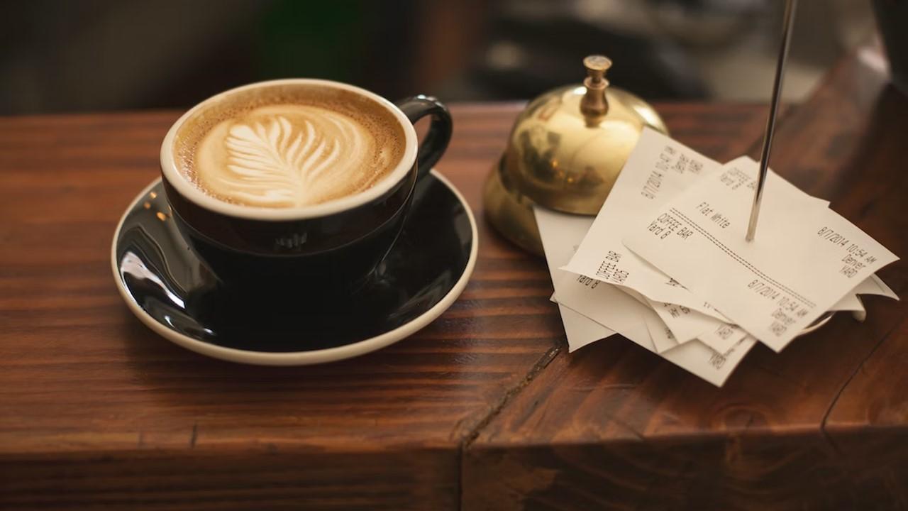 A stack of receipts near a cup of coffee