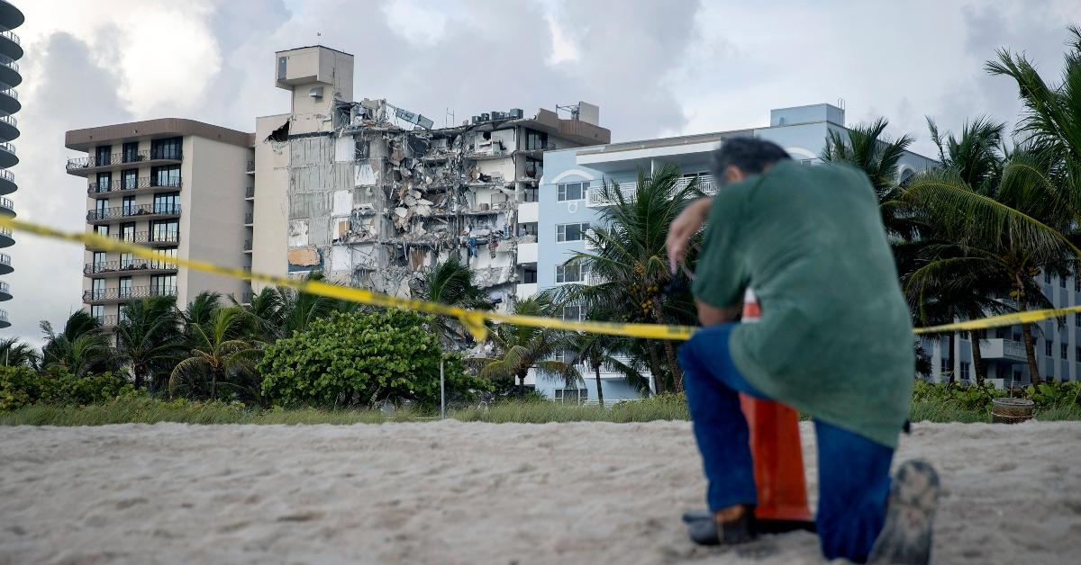 A man kneeling in front of the collapsed condo in Surfside, Florida