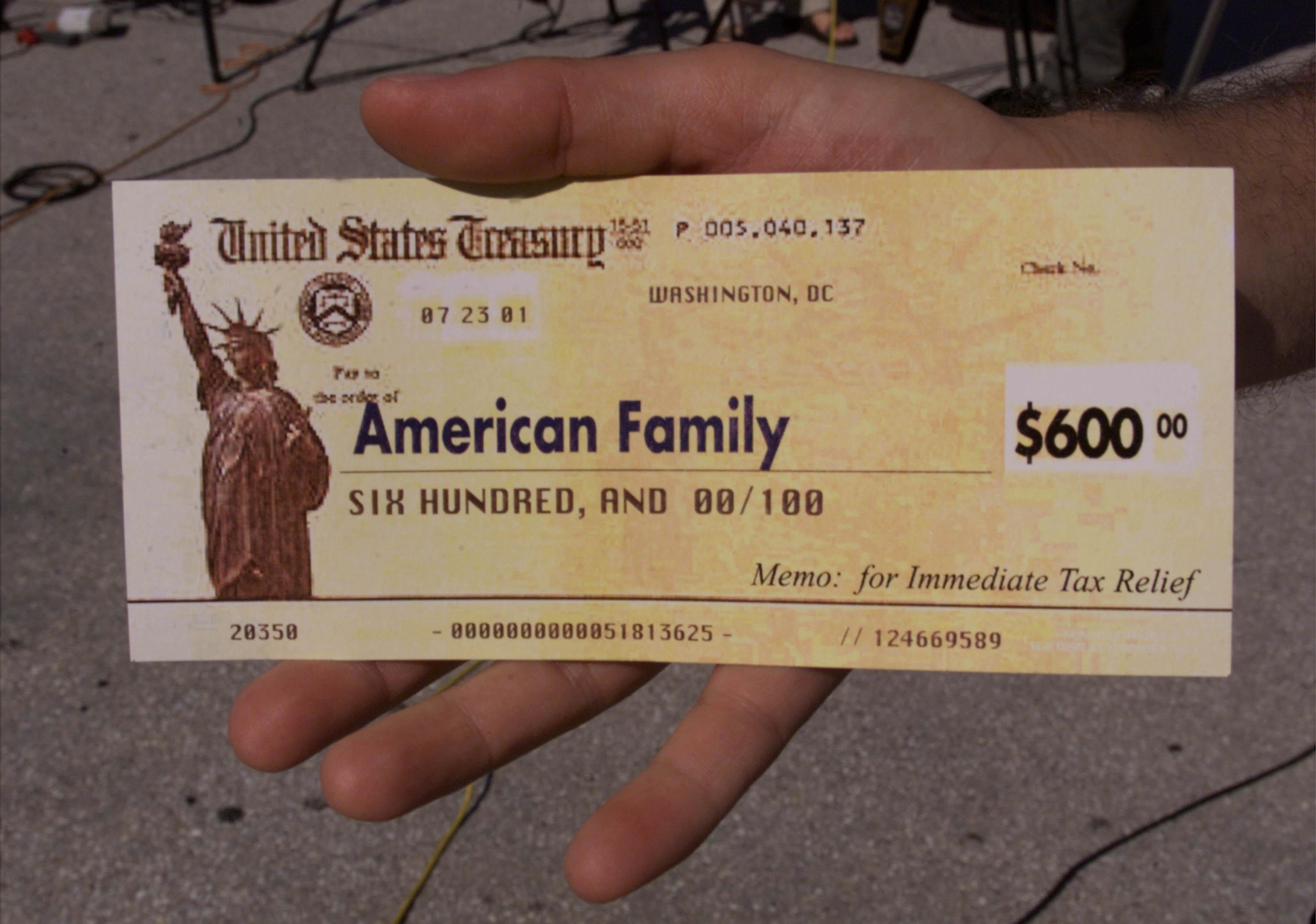 A man holds up a copy of a tax refund check