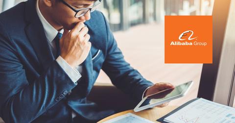 Man looking at data on a tablet and Alibaba logo