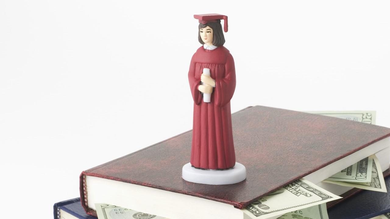 College graduate figure on a stack of books with money