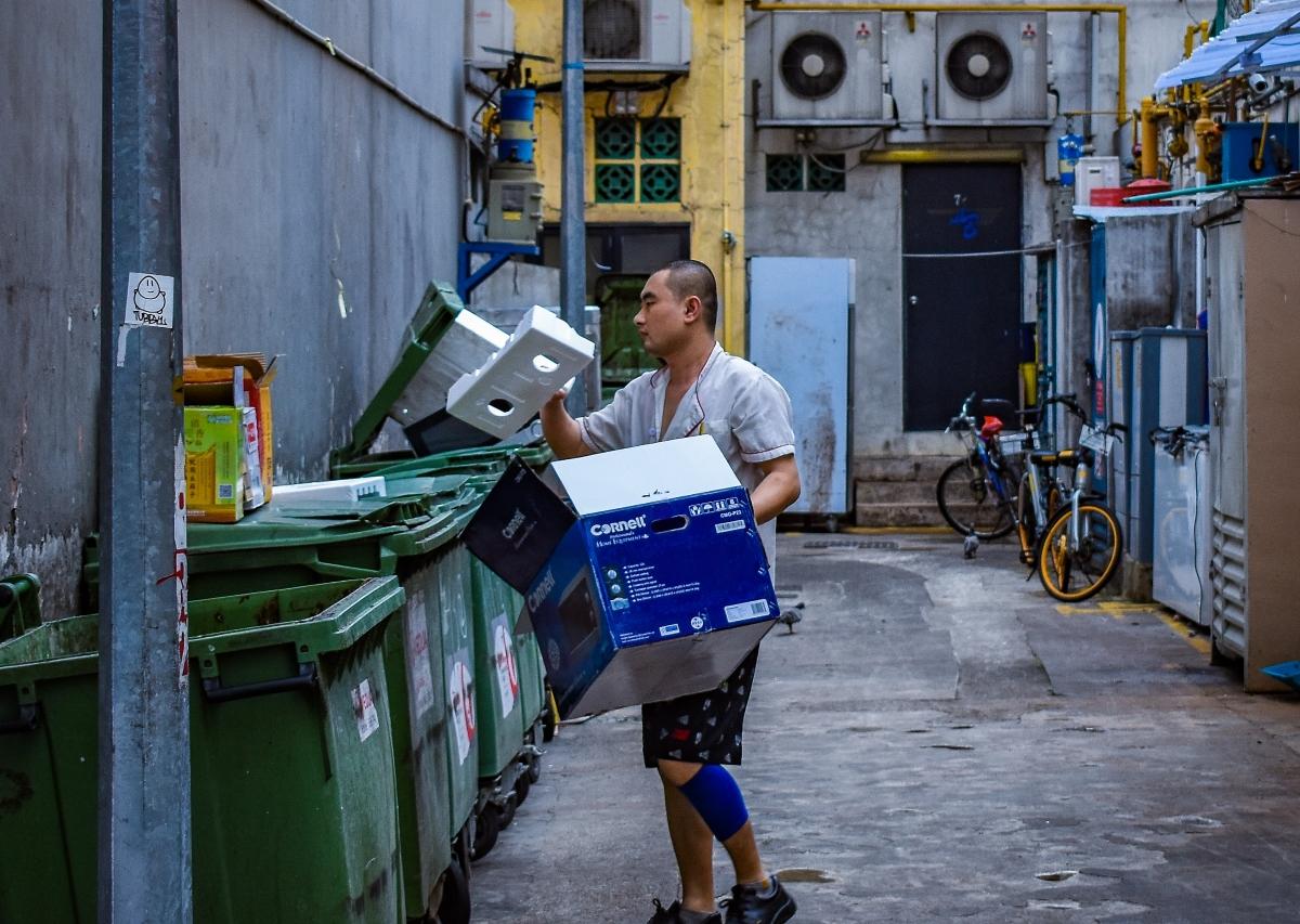 A man putting boxes in a dumpster