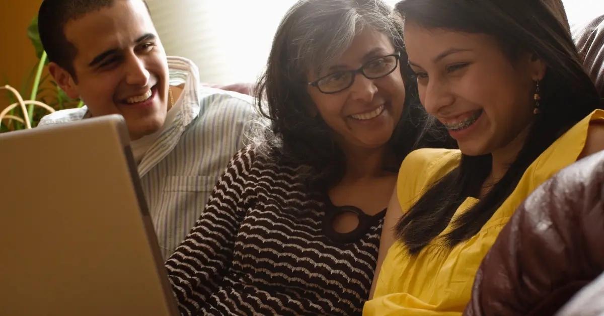 Parents sit with their teen daughter while filling out their tax forms online.