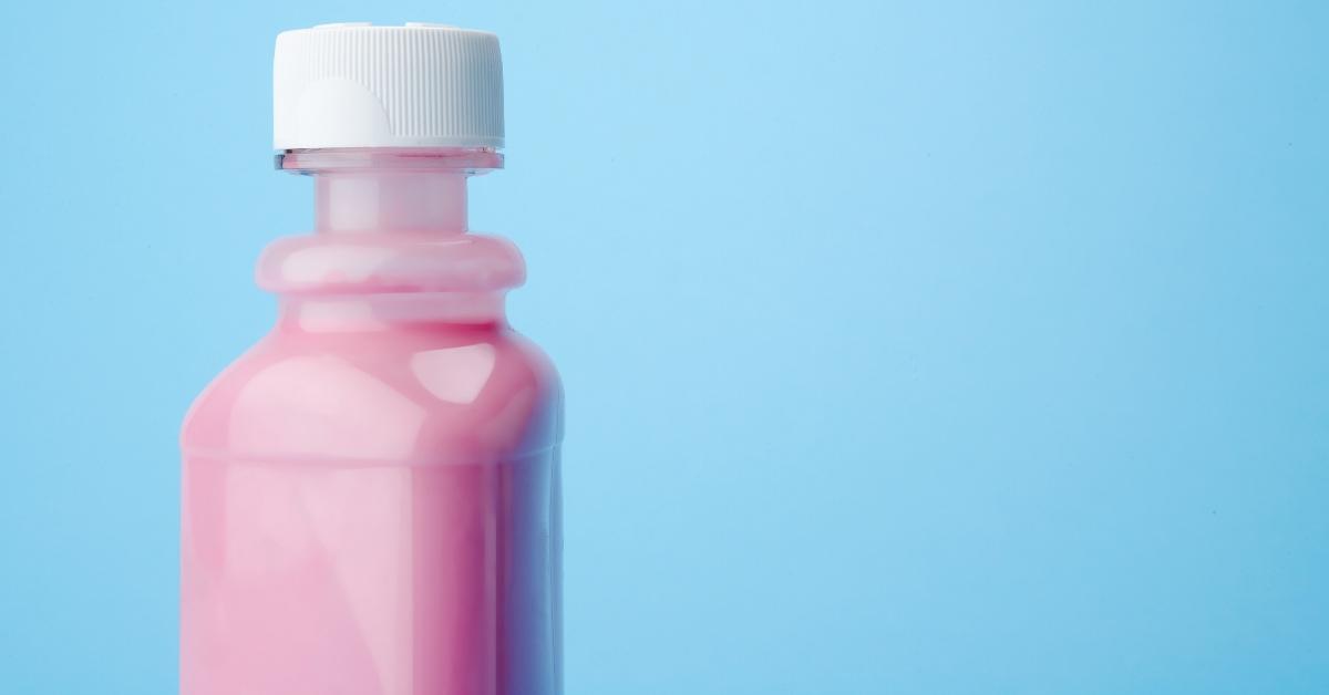 A bottle of pink liquid medicine with a blue background.