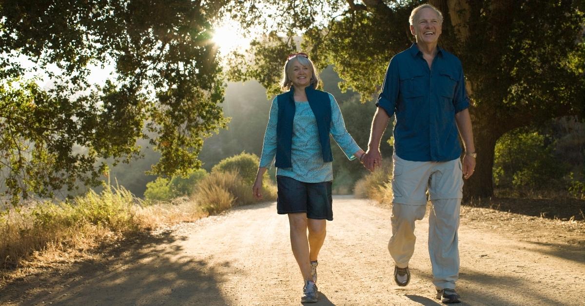 An older couple on a walk holding hancs.