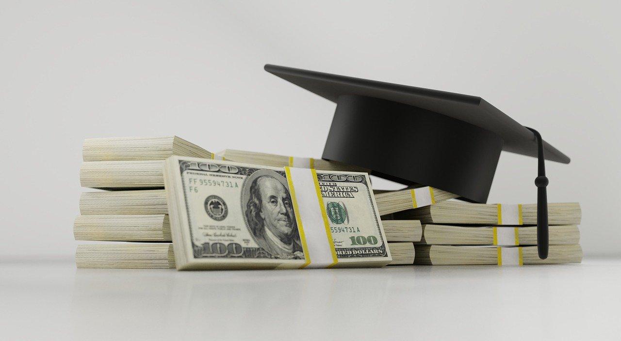 A graduation cap on a stack on money