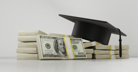 A graduation cap on a stack on money
