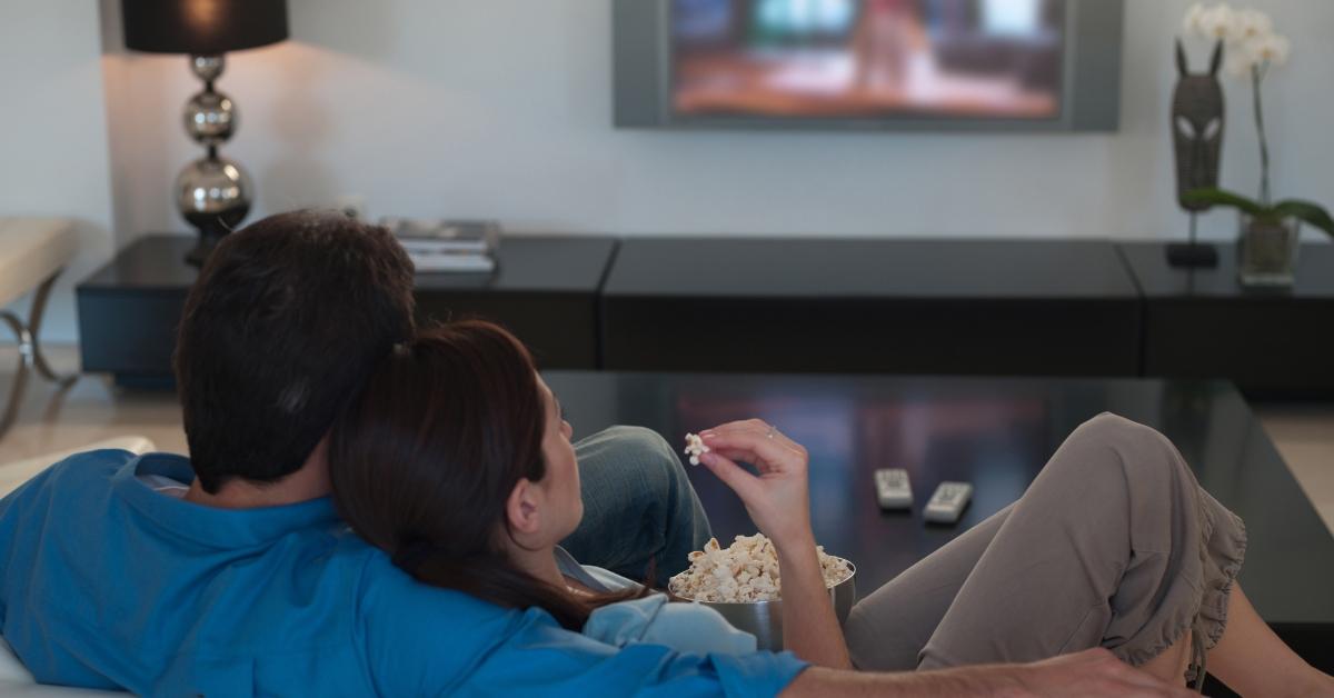 A couple eating popcorn at home