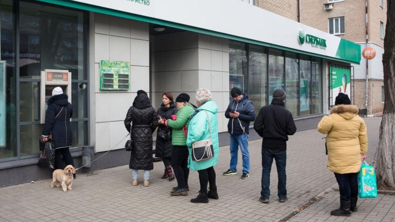 People in Ukraine line up at an ATM