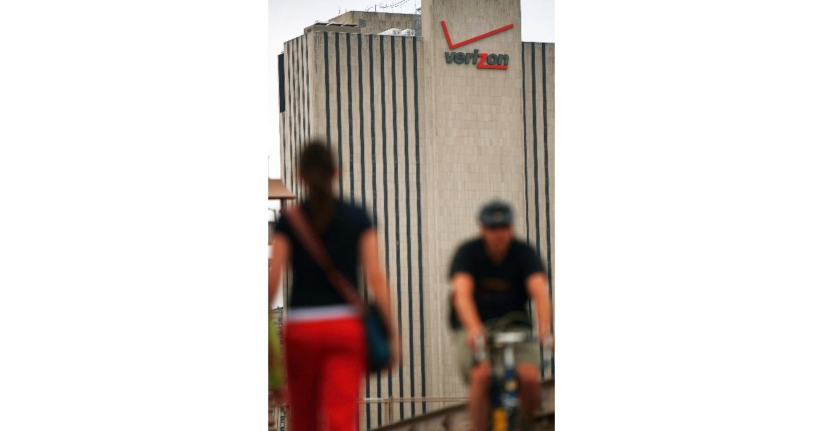 Pedestrians pass a Verizon logo on a building