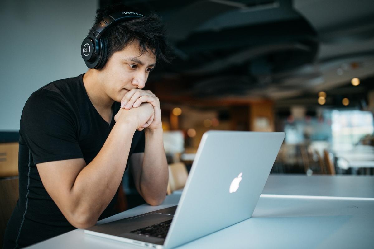 A male student with headphones and laptop