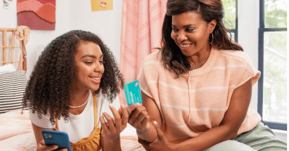 A mother excitedly hands her daughter her very first credit card.