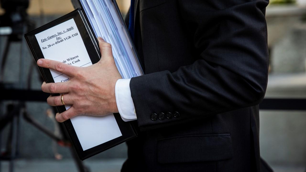 Lawyer holding Apple vs. Epic Games lawsuit evidence in binder