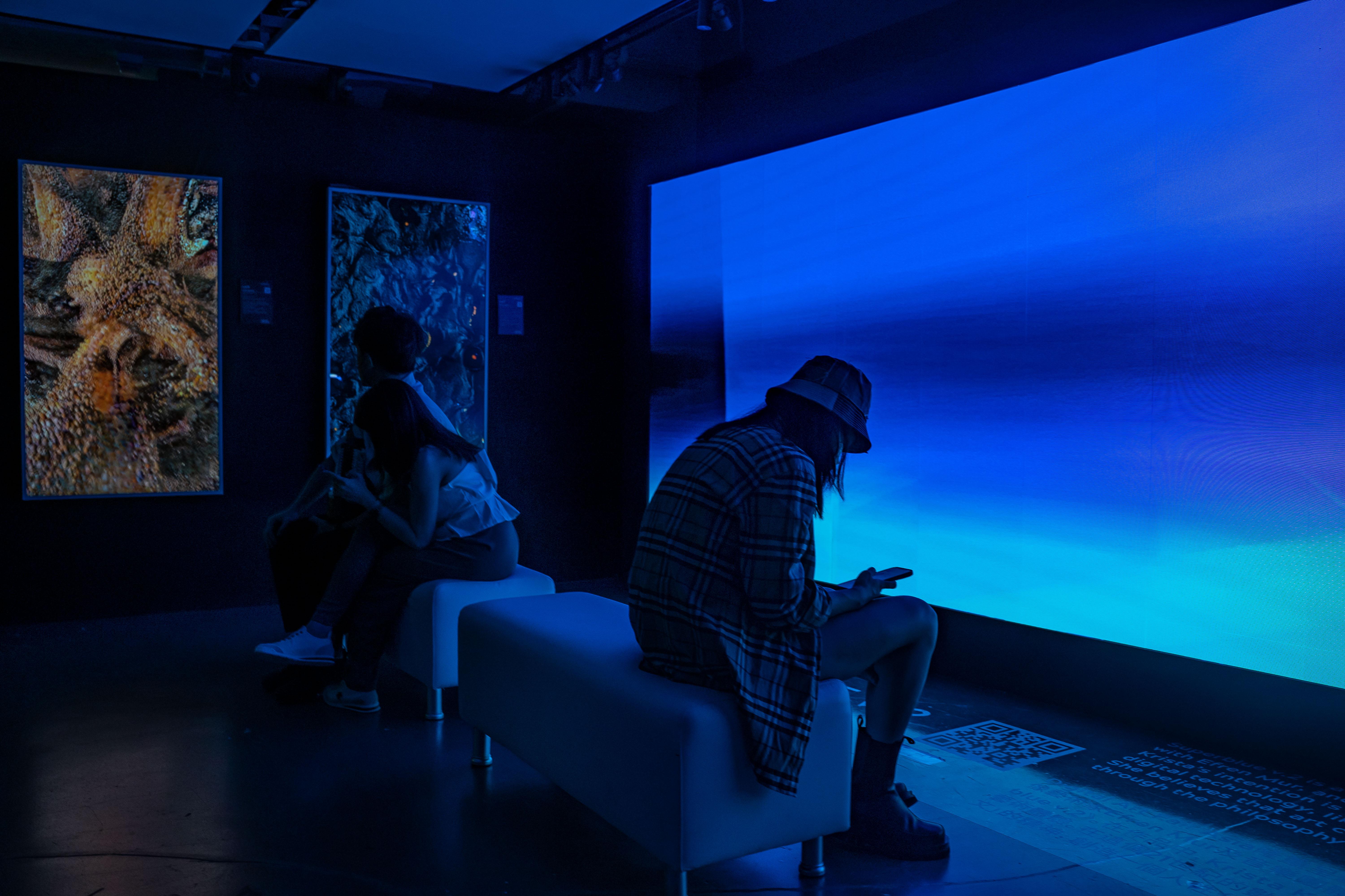 People using smartphones in front of an NFT gallery