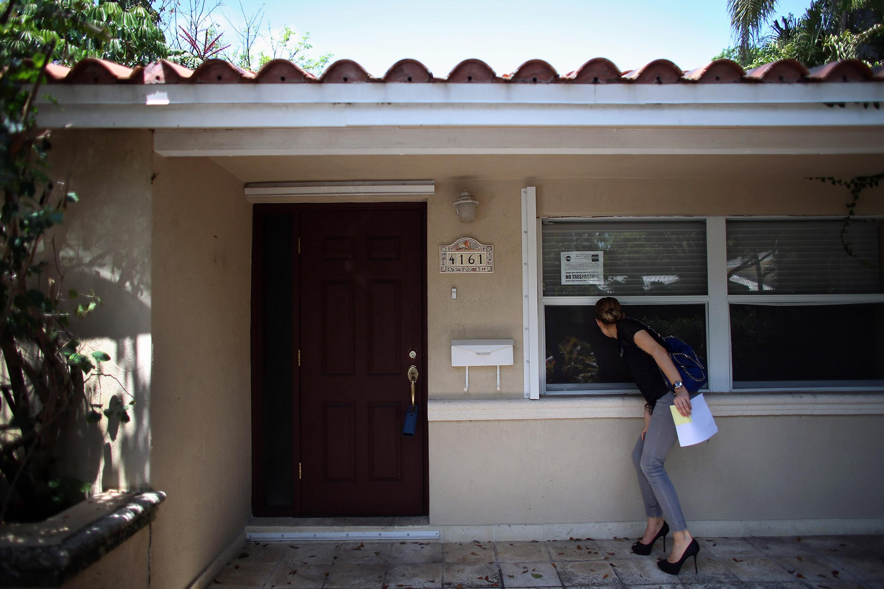 Person looking in window of foreclosed home