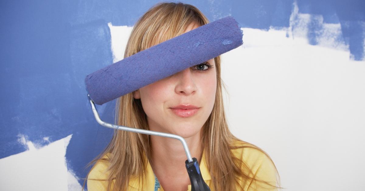 A person holding a roller covered in blue paint