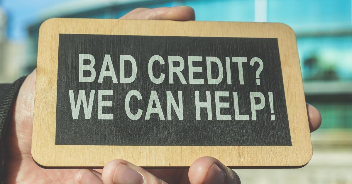 Hand holding sign that reads "Bad Credit? We Can Help!"