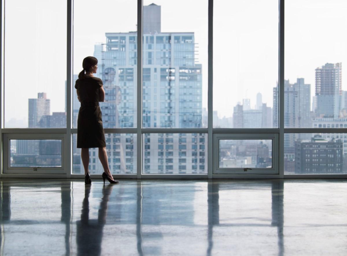 A woman in empty office looking outside