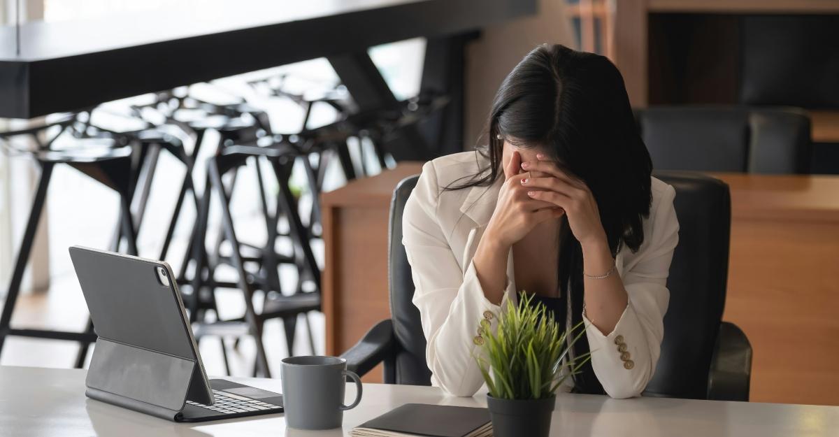 A woman holds her head in her hands while working.
