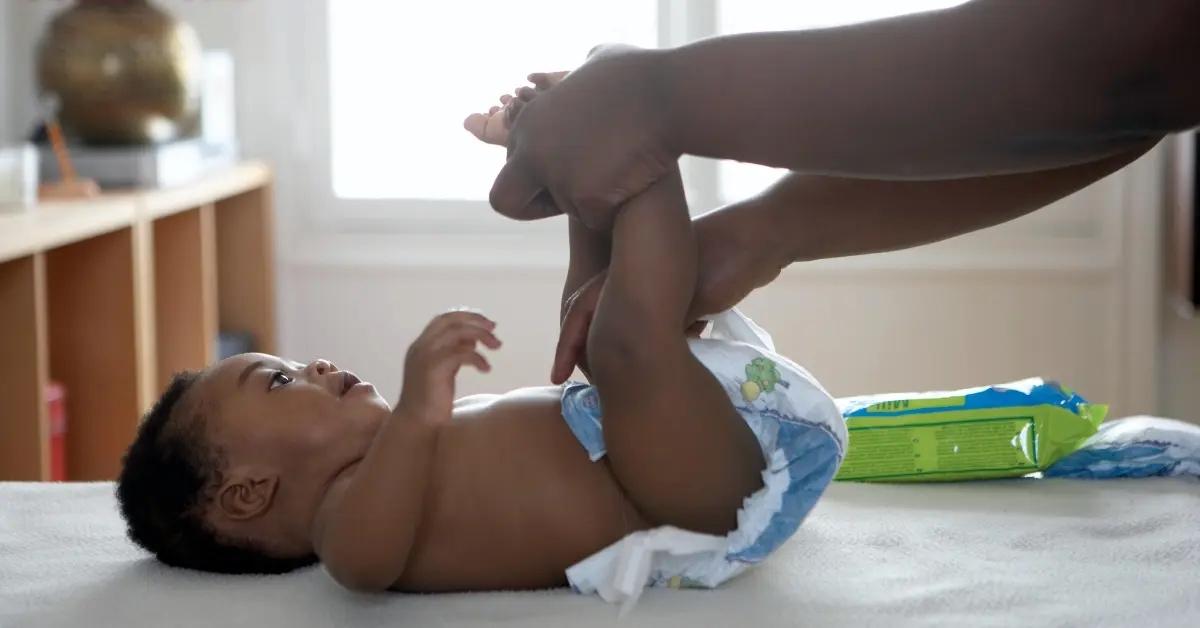 A small baby gets their diaper changed on a changing table.