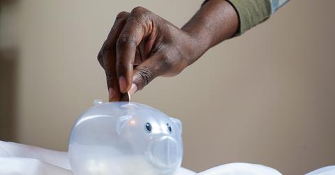 Person putting coin in a piggy bank