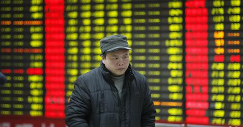 Person walking with Chinese stock tickers in background